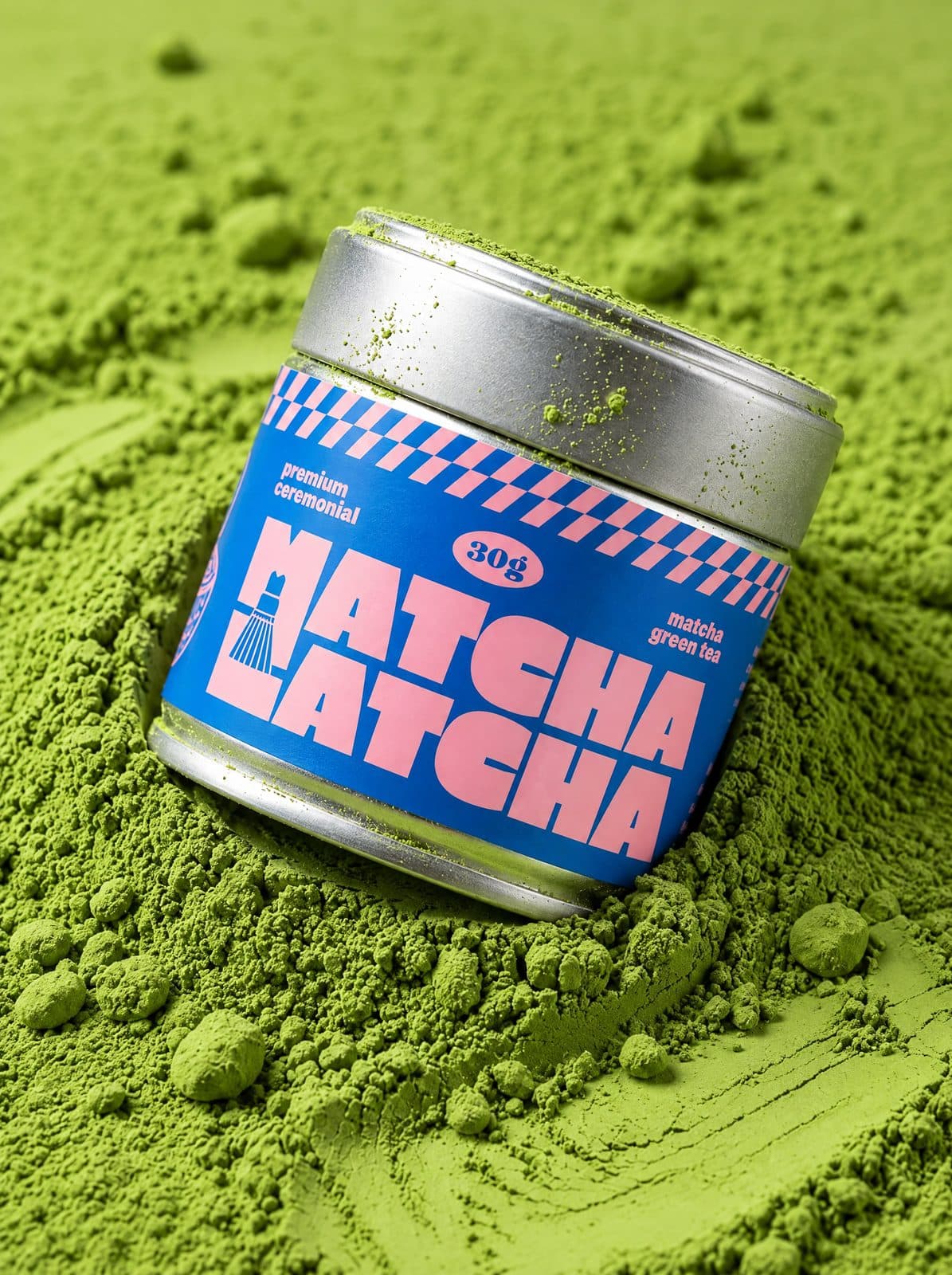 Plechovka Matcha Latcha zaborená v kope žiarivo zeleného matcha prášku